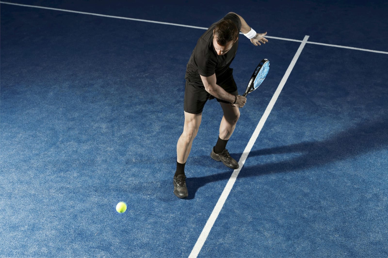 Jugador de pádel golpeando en una pista azul