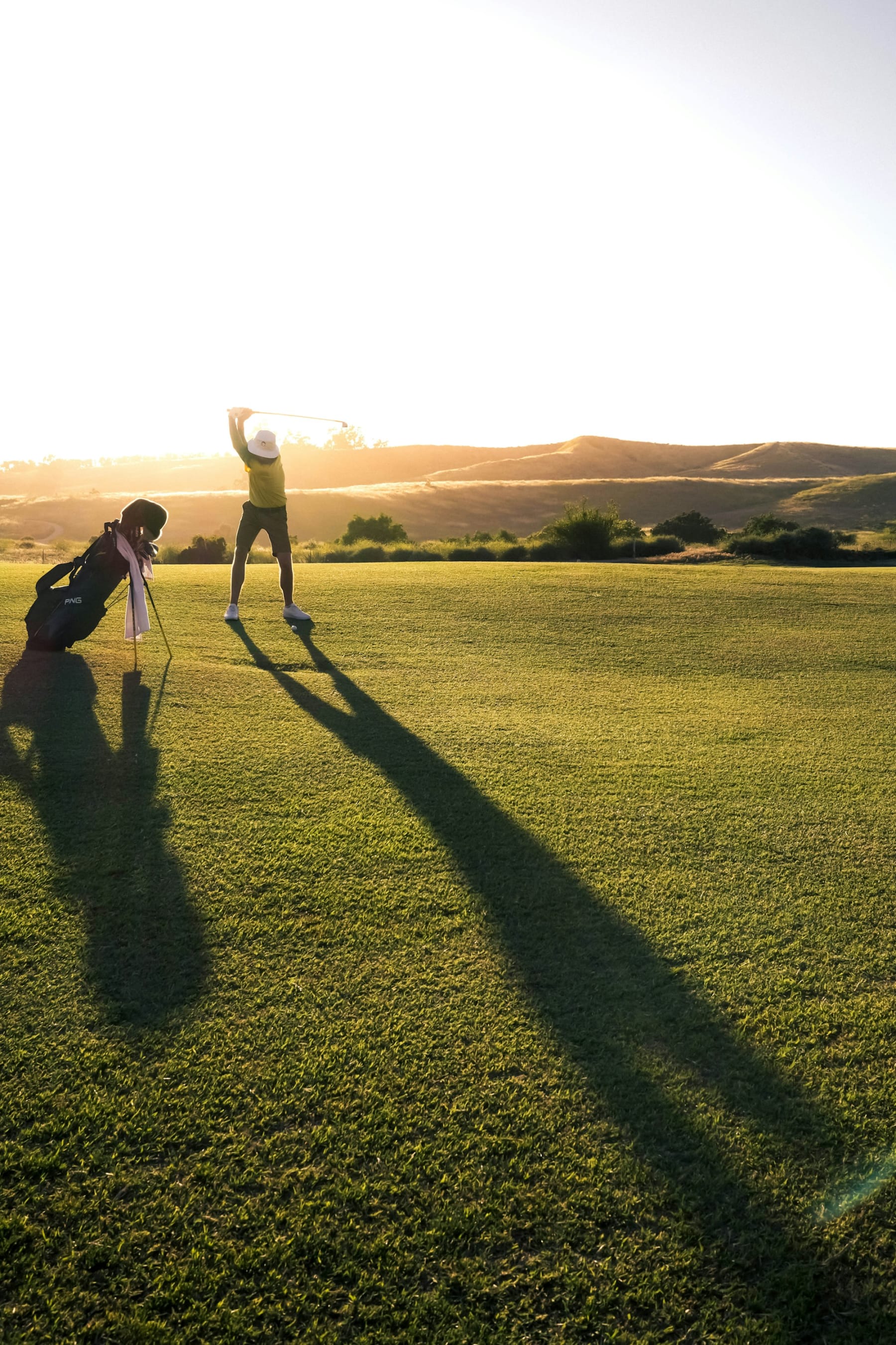 Golfista terminando el swing al atardecer